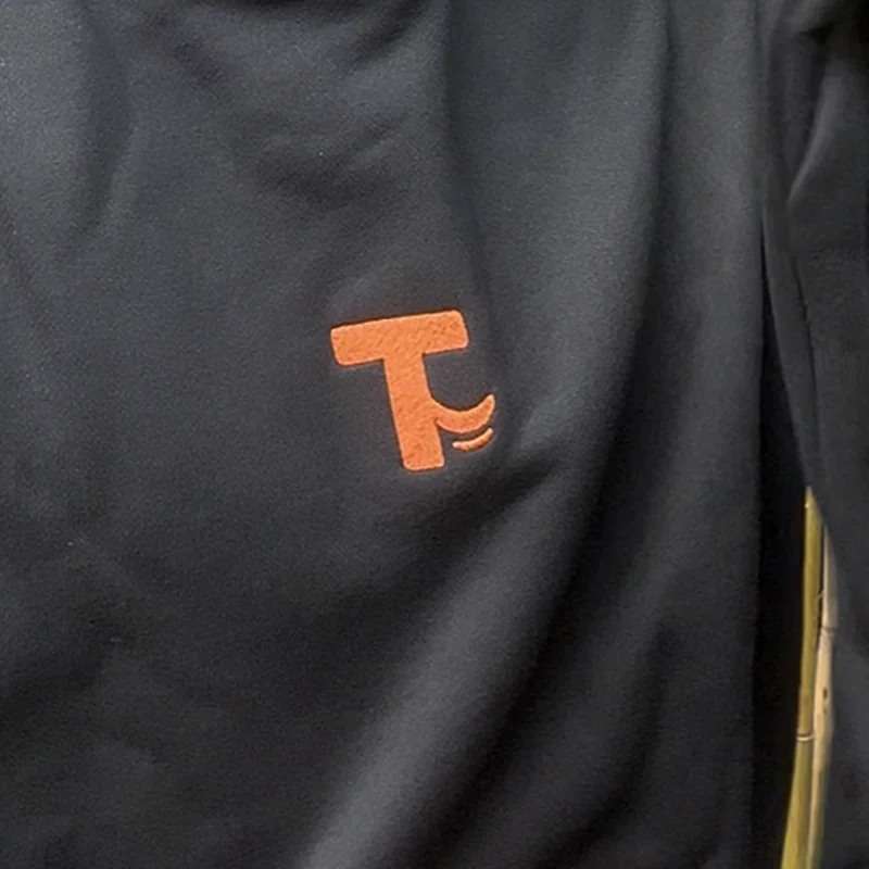 Close-up of the orange T-tail mark on the hoodie chest